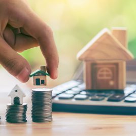 House on coins and house put on calculator. Man's hand putting home. planning savings money of coins to buy a home concept for property ladder, mortgage and real estate investment. saving for a house.